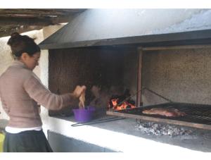 a woman is cooking food in an oven at GuardiaPiemontese Aparts in Capilla del Monte