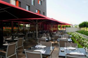 a restaurant with tables and chairs and umbrellas at Holiday Inn Mulhouse by IHG in Mulhouse