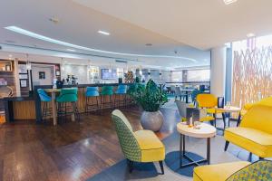 a restaurant with yellow and blue chairs and a bar at Holiday Inn Mulhouse by IHG in Mulhouse