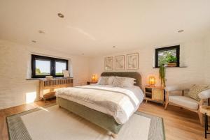 a bedroom with a bed and a chair and windows at Treloggas Retreat in Truro
