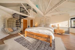 a bedroom with a large bed and a hanging chair at Treloggas Retreat in Truro