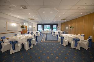 a banquet hall with white tables and chairs with blue bows at Holiday Inn Newport by IHG in Newport +98 photos
