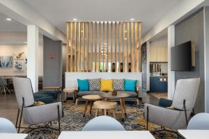 a lobby with a couch and tables and chairs at TownePlace Suites by Marriott Minot in Minot