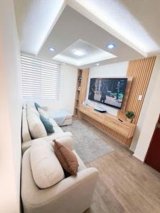 a living room with two white couches and a flat screen tv at Modern and cozy in Riobamba in Riobamba