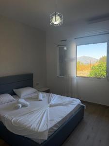 a bedroom with a large white bed with a window at Mateo Apartaments in Vlorë