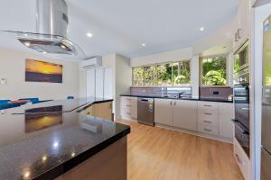 a kitchen with white cabinets and black counter tops at Getaway Ocean Views KIDS STAY FREE in Airlie Beach