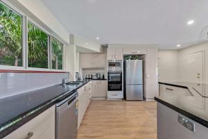 a large kitchen with white cabinets and a refrigerator at Getaway Ocean Views KIDS STAY FREE in Airlie Beach