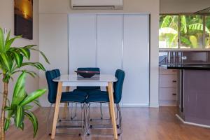 a kitchen with a table and blue chairs at Getaway Ocean Views KIDS STAY FREE in Airlie Beach
