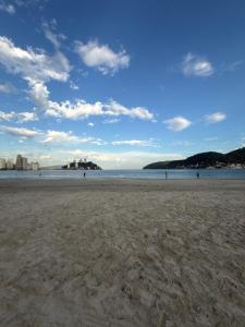 a sandy beach with people in the water at ApêBrisa73 in São Vicente