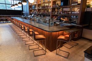 a bar with a row of stools in a restaurant at Kimpton Cardinal Hotel by IHG in Winston-Salem