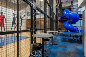 a room with a blue slide and tables at Kimpton Cardinal Hotel by IHG in Winston-Salem