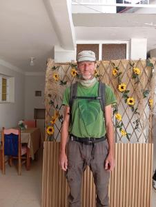 a man is standing in a room with sunflowers at Abril Hostel in Mollepata +1 photo
