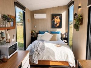 a bedroom with a bed and a tv and windows at Field and Fleece Farm Stay by Tiny Away in Claremont +17 photos
