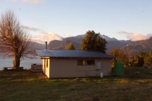a small house on a hill with mountains in the background at El Tilo Cabin - Hot Tub & Lake Ranco Views in Lago Ranco