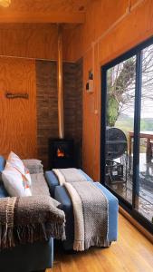 a bedroom with a fireplace and a bed with blankets at El Tilo Cabin - Hot Tub & Lake Ranco Views in Lago Ranco