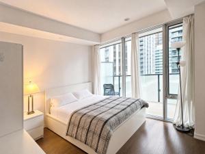 a white bedroom with a bed and a large window at The C Park Hotel and Suites in Toronto