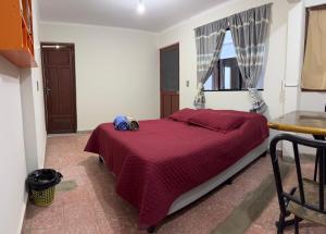 a bedroom with a bed with a red comforter and a window at Tango in Sucre