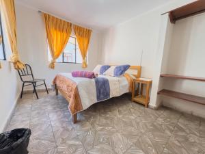 a bedroom with a bed and a chair and a window at Tango in Sucre