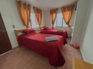 two beds in a bedroom with red blankets and windows at Tango in Sucre