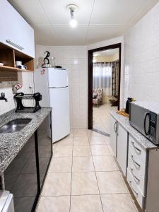 a kitchen with a white refrigerator and a sink at Casa à Beira Mar em Praia Seca Araruama RJ in Araruama