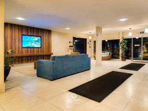 a lobby with a blue couch and a flat screen tv at Kaakupe Praia Hotel in Guaratuba