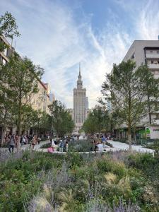 a park with a building in the background with people walking around at Prestige Center Warsaw Rooms Metro, AC, Smart TV, 2 Bathrooms in Warsaw
