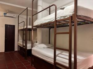 a room with three bunk beds with white sheets at Hostal Casa Lulú Santa Marta in Santa Marta