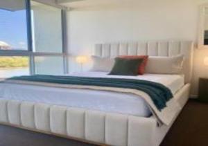a white bed in a room with a large window at Nature Meets City on Mint in Townsville +12 photos