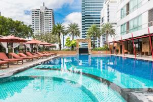 a pool with a pool table and chairs in front of a building at Ascott Sathorn Bangkok - SHA Plus Certified in Bangkok
