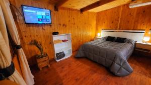 a bedroom with a bed and a flat screen tv at Cabañas Pulmahue in Colón
