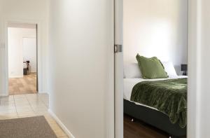 a bedroom with a bed with a green comforter at Hamptons on the Bay in Swansea