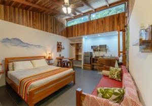 a bedroom with a large bed and a kitchen at Aves de Tierras Altas in Bijagua