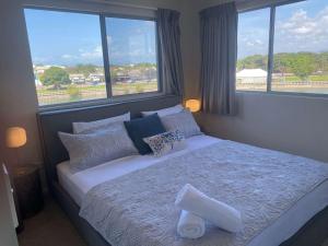 a bedroom with a large bed with pillows and windows at Tranquil 3 Bedroom Retreat in Townsville City in Townsville