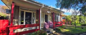 a red house with two chairs on the front porch at Serendip in Point Lonsdale