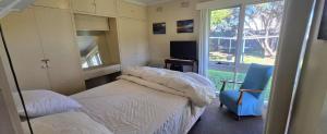 a bedroom with a bed and a chair and a window at Serendip in Point Lonsdale