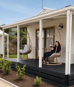 a woman sitting on the front porch of a house at BIG4 Robe Lakeside Tourist Park in Robe