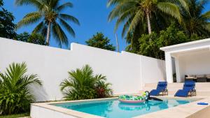 a swimming pool with blue chairs and palm trees at Old Harbour Oasis in Old Harbour +4 photos