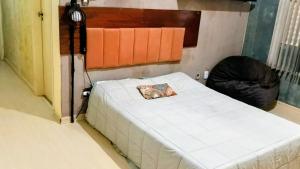 a bedroom with a white bed with a black frame at Fenergia Hospedagem Flexível in Pouso Alegre