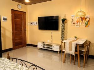 a dining room with a table and a television on the wall at Bahay Domingo Guesthouse & Private Pool in Bagac
