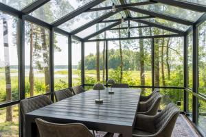 a dining room with a table and chairs in front of windows at Gauja Lakeside in Gauja