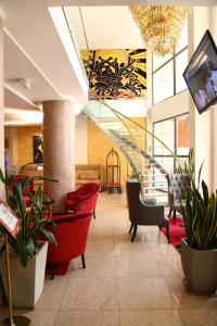 a lobby with red chairs and a staircase in a building at Hôtel Fleur de Lys Plateau in Dakar