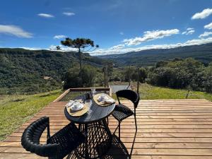 a table and chairs on a wooden deck with a view at Altos do Perito Cabanas in Alfredo Wagner