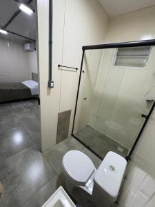 a bathroom with a toilet and a glass shower at Contêineres em Bombinhas in Bombinhas