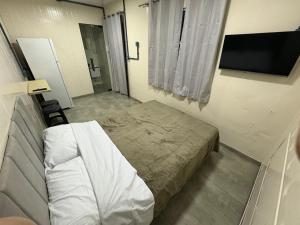 a small bedroom with a bed and a television at Contêineres em Bombinhas in Bombinhas