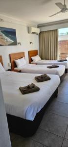 a group of three beds in a hotel room at Port O'Call Motel in Port Macquarie