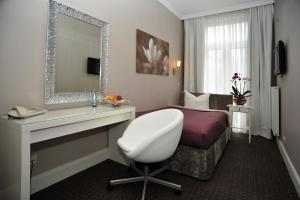 ハンブルクにあるホテル コモドーレのベッドと白い椅子が備わるホテルルームです。