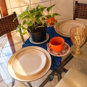 a table with two plates and a potted plant on it at Apartamento no Centro da Cidade Nova in Marabá +1 photo