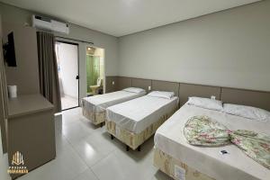 a hotel room with two beds and a balcony at Pousada Maranata in Aparecida
