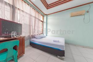 a bedroom with a bed and a desk and a tv at Bojongsoang Guesthouse RedPartner in Bandung