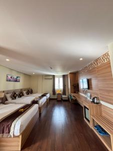 a hotel room with three beds and a desk at Sen Vàng Luxury Hotel in Nha Trang